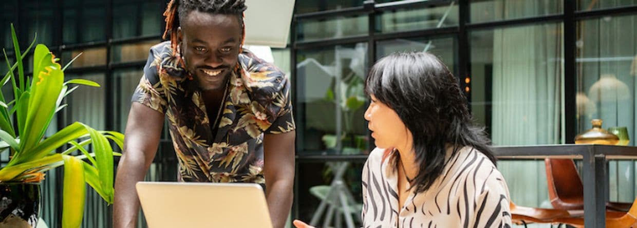 Two people, a man and a woman, talking in front a computer