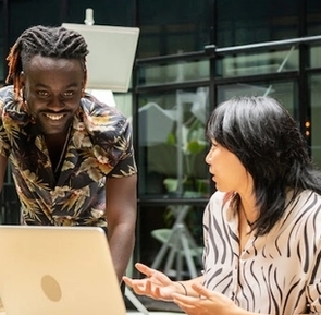 Two people, a man and a woman, talking in front a computer